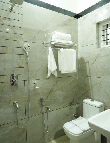 a bathroom with a shower with a toilet and a sink at AVANTI CASTELLO in Guruvāyūr