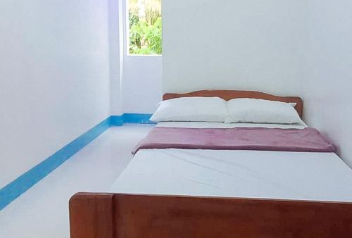 RedDoorz @ SCJS INN Buug Sibugay في Buug: سرير في غرفة بيضاء مع