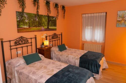 two beds in a room with orange walls at La Casita de Lucia in Trescasas
