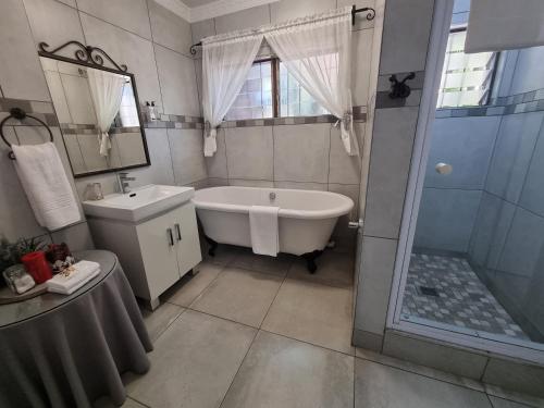 a bathroom with a tub and a sink and a shower at Ndiza Lodge and Cabanas in St Lucia