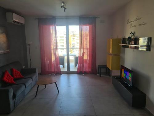 a living room with a couch and a tv at St Julians Bay Sea Front Apartments in St Julian's