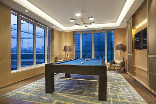 a pool table in a room with windows at Somerset Grand Central Dalian in Dalian