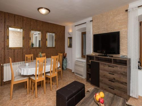 a dining room with a table and a flat screen tv at Holiday Home By The Sea - Nina & Kate in Ston