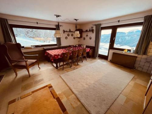 uma sala de jantar com mesa, cadeiras e janelas em Haus an der Planai (Pistenzugang & Panoramablick) em Schladming