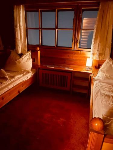 a room with two beds and a desk and windows at Haus an der Planai (Pistenzugang & Panoramablick) in Schladming
