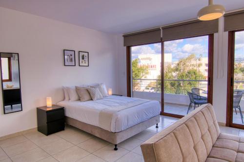 a bedroom with a bed and a couch and a balcony at Phaedrus Living: City Flat Palas 103 in Paphos City