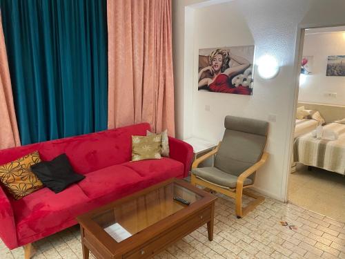 プラヤ・デル・イングレスにあるApartment 4th floor Yumbo Centrumのリビングルーム(赤いソファ、椅子付)