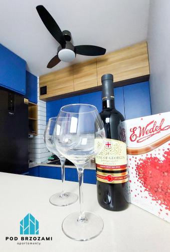 a bottle of wine and two wine glasses on a counter at Pod Brzozami Apartamenty Let's Sea Gąski in Gąski