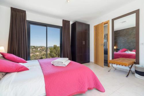 a bedroom with a large bed with a pink blanket at Luxury Sitges Hills Villa in Olivella