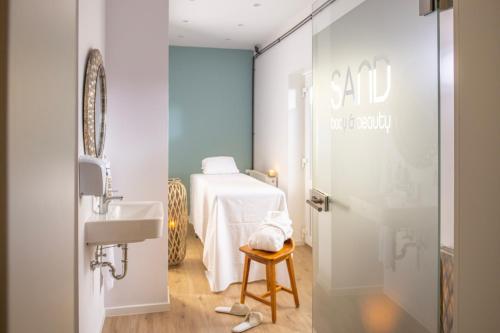 łazienka z umywalką i łóżkiem w pokoju w obiekcie SAND Lifestylehotel w mieście Timmendorfer Strand