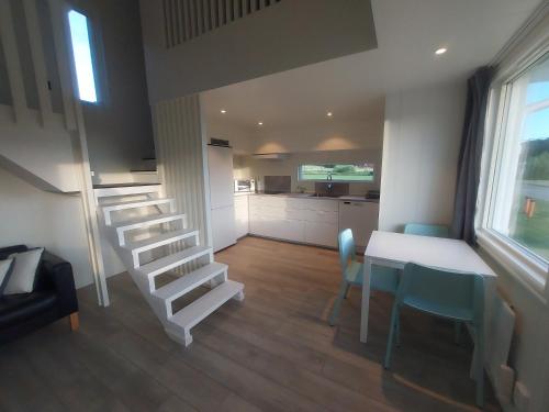 ein Wohnzimmer mit einer Treppe, einem Tisch und Stühlen in der Unterkunft Havsnära Stuga in Klövedal