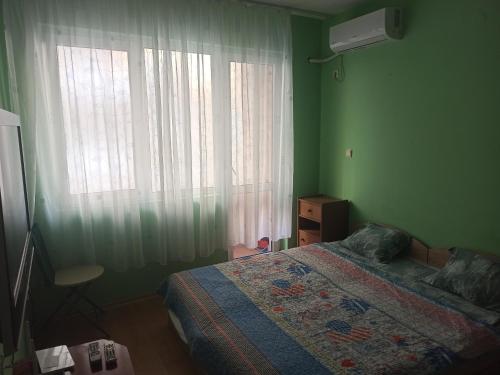 Dormitorio verde con cama y ventana en Апартамент Александр 1, en Burgas