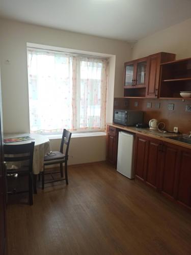 a kitchen with wooden cabinets and a table and chairs at Апартамент Александр 1 in Burgas City
