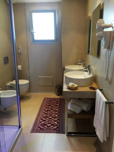 a bathroom with a sink and two toilets and a window at Hotel Calabona in Alghero