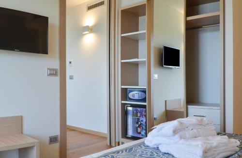 a room with a bed with a tv and a mirror at Hotel Calabona in Alghero