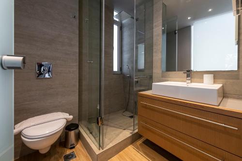a bathroom with a toilet and a sink and a shower at Phaedrus Living: Luxury Flat Vouliagmeni in Athens