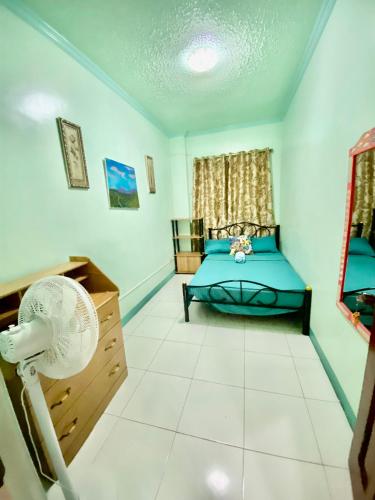 a bedroom with a blue bed and a fan at Panabo Furnished house-Downstairs in Panabo