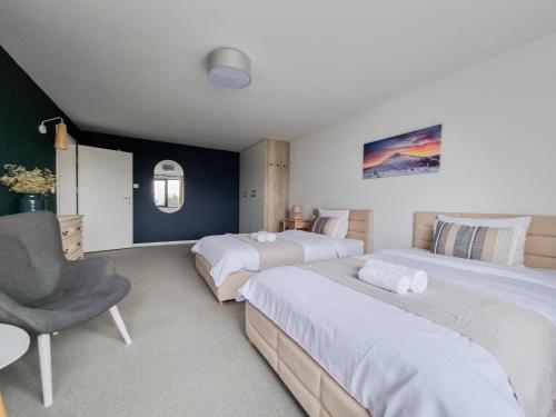 a bedroom with two beds and a chair in it at Sporthaus Sosnówka - Deluxe Villa & Garden in Sosnówka
