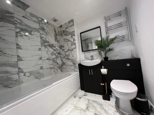 a bathroom with a toilet and a sink and a tub at Modern 2 Bedroom Aesthetic Apt in Manchester