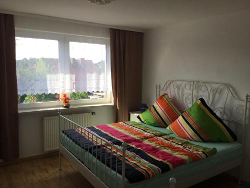 a bed with colorful pillows in a bedroom with a window at Bei Netti in Klütz