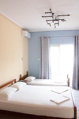 two beds in a room with a window at ELENI in Paralia Katerinis