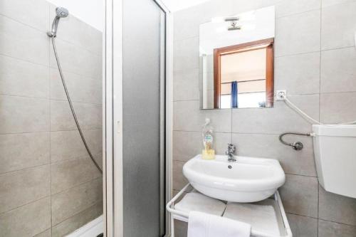 Baño blanco con lavabo y espejo en Residencial Lareira do Pinheirinho en Almada