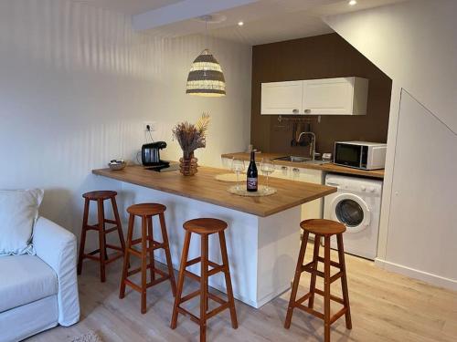 a kitchen with a counter and bar with stools in it at Suite cosy au cœur de Vinzelles proche Mâcon Tout équipé avec salon d'extérieur in Vinzelles