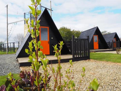 a house with an orange door and a black roof at Carrowmena Family Glamping Site & Activity Centre in Limavady