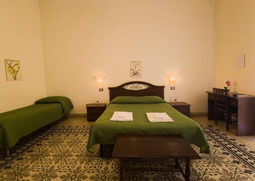 ein Schlafzimmer mit einem grünen Bett und einem Tisch in der Unterkunft B&B Liberty in Palermo
