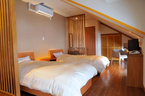 a hotel room with two beds and a tv at Maruyama Onsen Kojyokan in Minami Uonuma