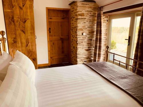 a bedroom with a large white bed with a window at Detached Barn in Tamar Valley, EV charging included in Yelverton