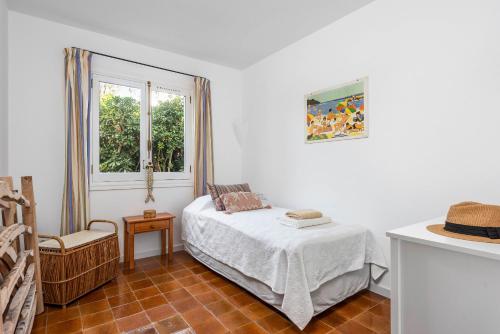 a small bedroom with a bed and a window at Casa Esquinera - Villa en Trebaluger in Es Castell