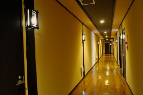 an empty hallway with yellow walls and wooden floors at Maruyama Onsen Kojyokan in Minami Uonuma