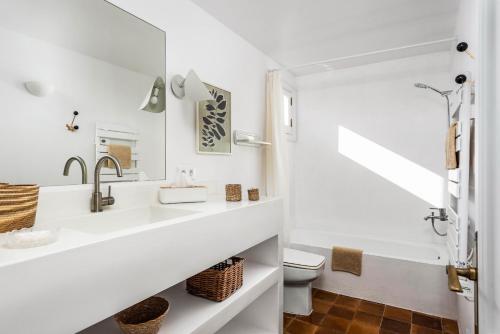 a white bathroom with a sink and a toilet at Casa Esquinera - Villa en Trebaluger in Es Castell