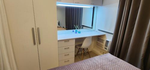 Azure urban residences 1BR Unit fits max 3 persons في مانيلا: غرفة نوم مع مكتب ومرآة وسرير