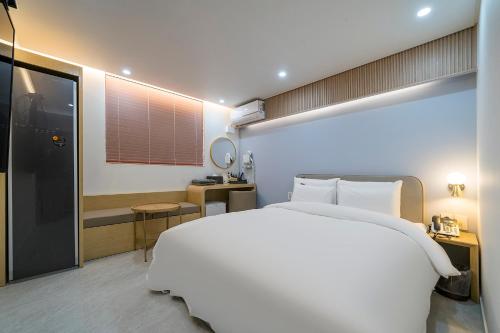 a bedroom with a large white bed and a bathroom at Browndot Hotel Namchuncheon in Chuncheon