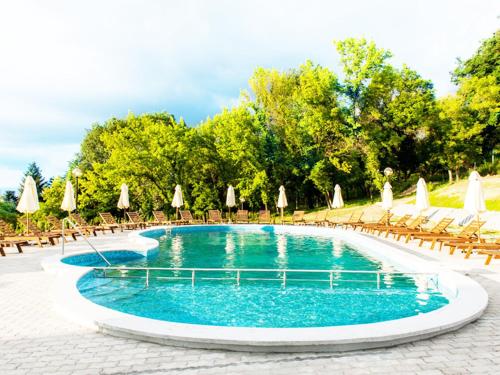 a swimming pool with chairs and umbrellas at Парк хотел Кюстендил in Kyustendil