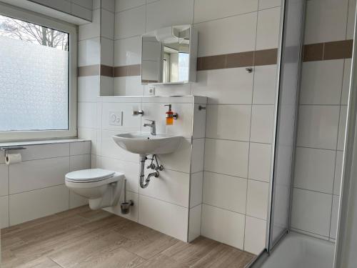 bagno con servizi igienici, lavandino e specchio di M&M Hotel - Neu Wulmstorf a Neu Wulmstorf