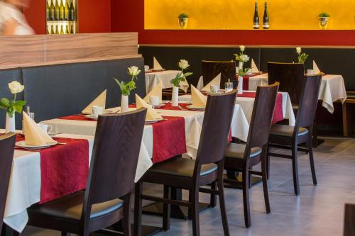 a row of tables in a restaurant with red and white table settings at Weingut Schreieck VINOTEL & GUTSHAUS in Sankt Martin