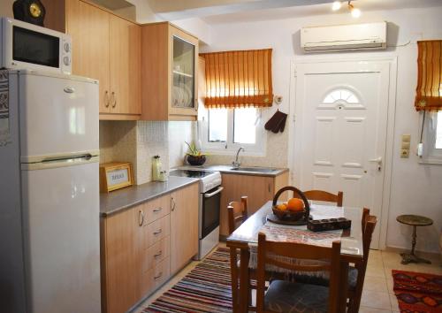 a kitchen with a table and a white refrigerator at Ethia 2Floor Mountain View Cottage garden wifi ac in Ethiá