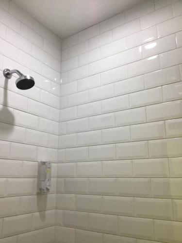 a bathroom with a white tiled wall and a shower at Bandung Hostel in Bandung