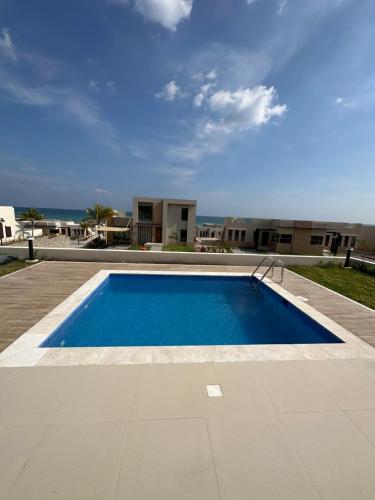 a large swimming pool with the ocean in the background at The Beach House in Muscat