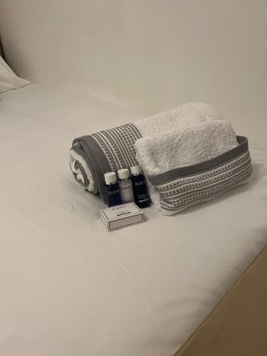two towels and a book sitting on a bed at TJ Homes - Luxury Studio Suite with Garden View - Next to tube station London in Ruislip