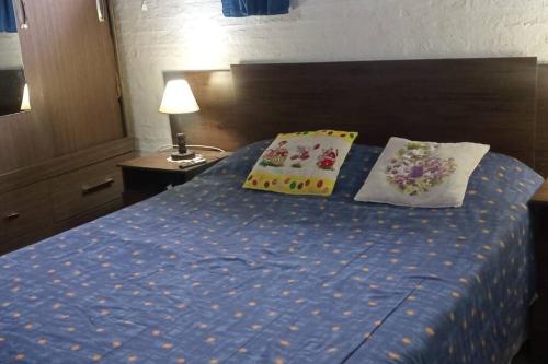 1 dormitorio con 1 cama azul y 2 almohadas en casa en balneario Buenos Aires, en Balneario Buenos Aires
