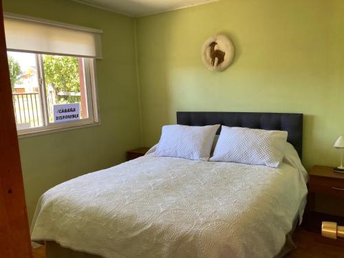 1 dormitorio con 1 cama grande con sábanas blancas y ventana en Terra Patagónica, en Puerto Tranquilo