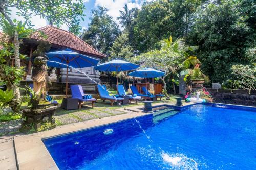 uma piscina com cadeiras azuis e guarda-sóis em Asli Bali Villas em Bangli