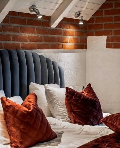 a bed with pillows on it with a brick wall at Villa Brunnby in Mölle