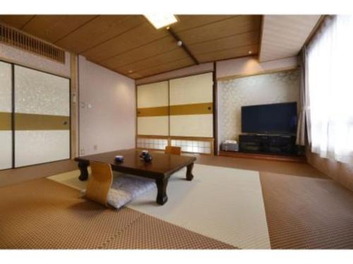 sala de estar con mesa y TV en Hotel Seiryu Japanese Ryokan Style Ishikiri Onsen, en Higashiōsaka