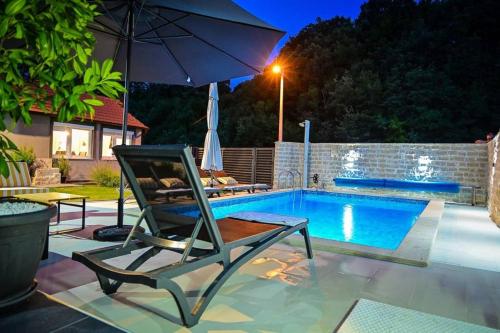 a chair and an umbrella next to a swimming pool at Villa Sierra in Sinj