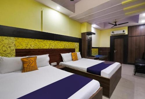 2 camas en una habitación de color amarillo y azul en Hotel Aditya Palace By WB Inn, en Kānpur